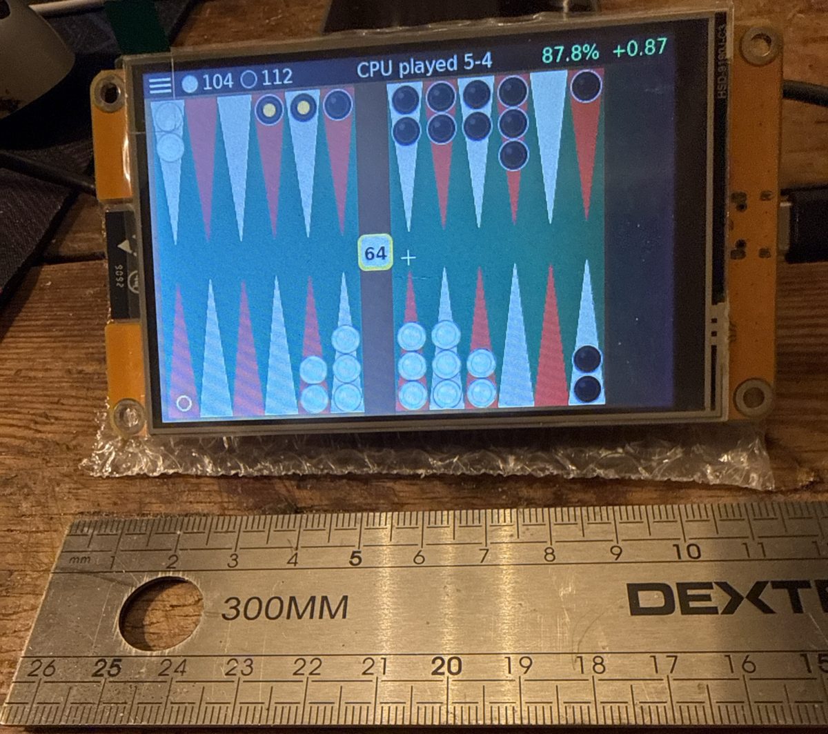 The 4-inch ESP32 touch-screen board playing Retro Backgammon, with a ruler in front showing it is about 11 cm wide