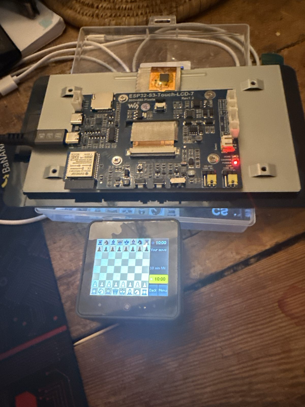 The back of the 7-inch Waveshare board, showing the ESP32-S3 module, two USB-C sockets and a microSD slot, with the CoreS3 playing in front